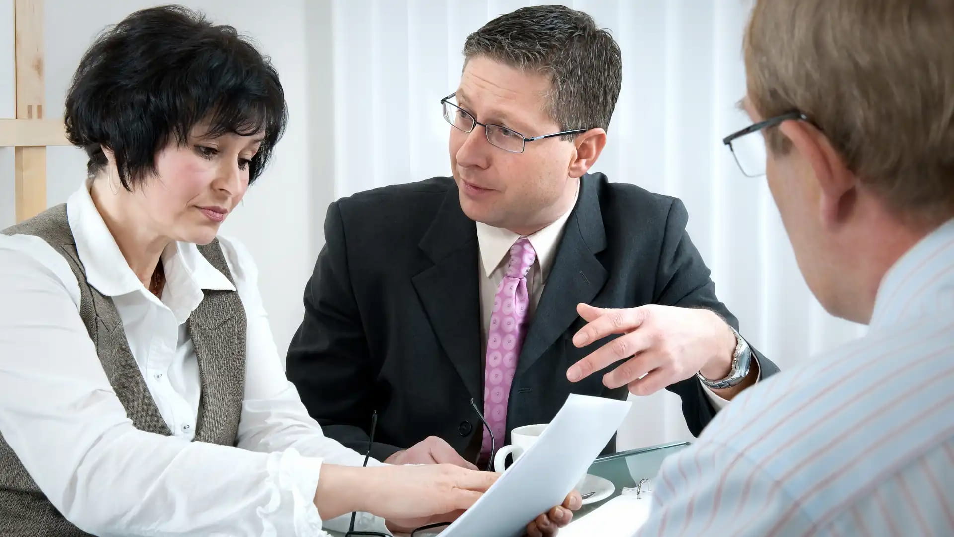 pictured a middle age couple discussing divorce settlement papers with their lawyer